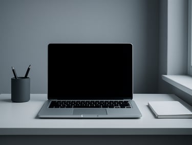 Straight-on architectural shot of a clean, minimalist home office desk with a laptop, illuminated by cool natural daylight from a side window, 35mm lens, high contrast slate and white tones.