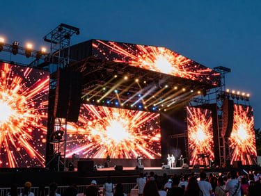 Detalle de sistemas de audio e iluminación de última generación en un gran escenario, con pantallas LED brillantes y efectos de luz dramáticos.