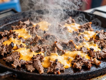 Extreme close-up of sizzling chopped meat and melted cheese on a hot flat-top grill, steam rising, vibrant saturated tones, 35mm street photography
