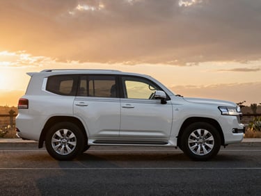 Cinematic side profile of a white Toyota LC300 on a clean paved road, dramatic sunset lighting.