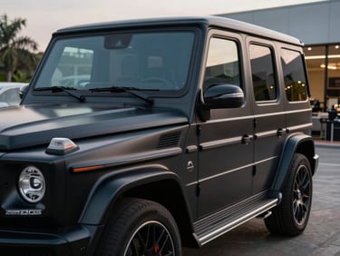 Close-up of a matte black Mercedes G63 AMG parked in a clean architectural showroom in Abidjan at twilight.