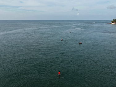 Wide aerial documentary shot of a coastal indigenous community in Panama, soft overcast daylight, deep green water