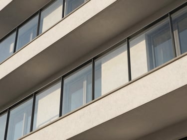 Architectural detail of a luxury apartment balcony with black steel railings, clean minimalist lines, soft morning light.