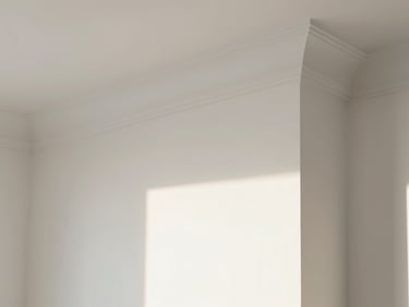 Close-up of a freshly painted white interior wall with crisp crown molding, bright natural light.