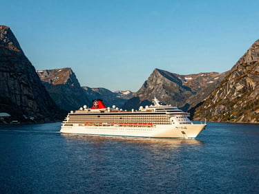 Luxury cruise ship sailing through a deep blue fjord under a bright clear sky, majestic mountains on the horizon.