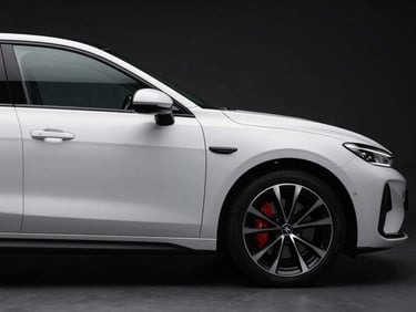 Sleek side profile of a modern white sedan, sharp body lines, dark background, studio lighting