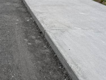 Close-up of a concrete path or slab, visible before-and-after split showing dark stained concrete transitioning to clean pale grey surface, overcast natural light