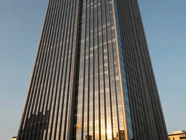 Wide architectural angle of a modern sun-drenched skyscraper in Cebu IT Park, golden-hour sunlight reflecting off glass panels, clean vertical lines.