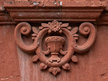 Detailed close-up of hand-carved baroque details on the red sandstone ruins of São Miguel, soft side lighting emphasizing texture.
