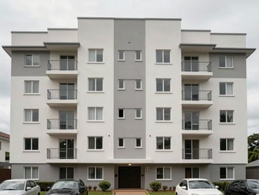 Straight-on exterior shot of a mid-rise apartment block in Accra, clean rendered facade, natural overcast daylight, parked cars visible at ground level showing scale