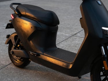 Sleek matte black electric scooter parked on a clean concrete pavement in Santo Domingo, dramatic golden hour reflection on the chassis, close-up profile, 35mm lens