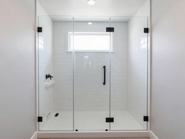 Bright modern bathroom remodel, straight-on wide-angle shot of a newly installed walk-in shower with white subway tile, clean glass enclosure, matte black fixtures, natural window light.