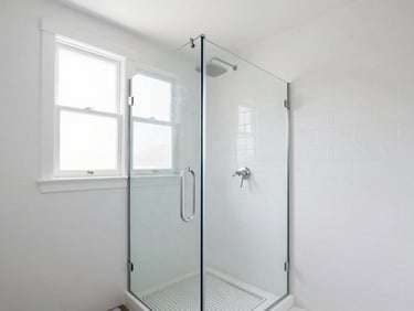Bright modern walk-in shower with a sleek glass panel, white subway tiles, brushed nickel fixtures, natural window light