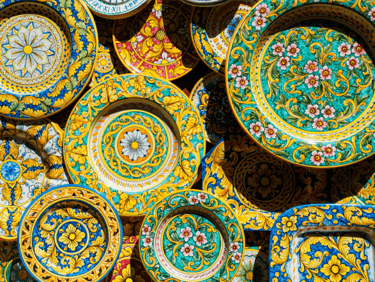 Hand-painted Italian maiolica ceramic plates with colorful Mediterranean floral and geometric patterns.