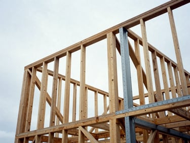 Low-angle architectural photograph of heavy timber framing and exposed structural steel beams against a crisp overcast winter sky, high contrast, 35mm