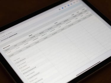 A close-up macro photo of a modern tablet screen displaying a clean, technical financial ledger with structured columns and sharp typography, warm late-afternoon light reflecting off the glass.