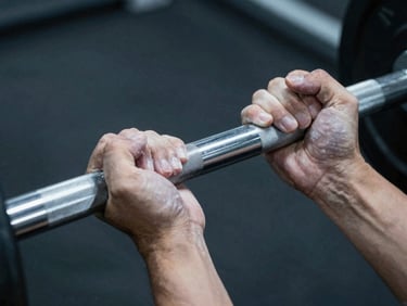 close-up of hands gripping a knurled steel barbell with chalk, focused overhead spotlighting, high contrast cool tones.