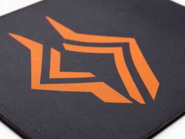 High-contrast studio shot of a technical gaming mousepad with orange geometric branding, clean stitching