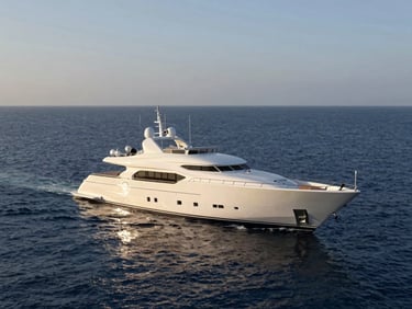 Wide environmental render of a superyacht at anchor in calm deep-blue water, late afternoon sidelight illuminating the hull profile, open ocean stretching to a hazy horizon, no crew visible, scale emphasized by surrounding sea