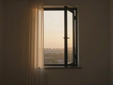 Cinematic still of a single open window at dusk, curtain edge in sharp focus left frame, the diffuse golden light beyond — shot in a quiet empty room, no people, minimal composition