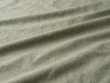 Close-up of a recycled fabric blend, showing subtle texture and modern finish, soft natural light, muted forest green and beige tones.