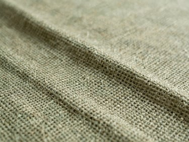 Close-up of woven natural jute fabric, showing texture and strength, soft natural light, muted forest green and beige tones.