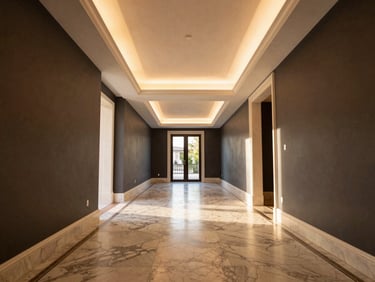 Wide-angle architectural photograph of a completed luxury villa hallway, showing perfect alignment of gypsum ceilings, recessed lighting, and marble flooring.
