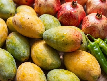 Vibrant display of fresh Indian mangoes, pomegranates, and green chilies, high-key studio lighting, rich saturated colors.