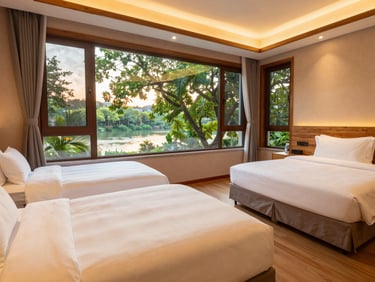 Spacious clean family resort room with two large beds, warm lighting, wooden accents, window overlooking lush green trees