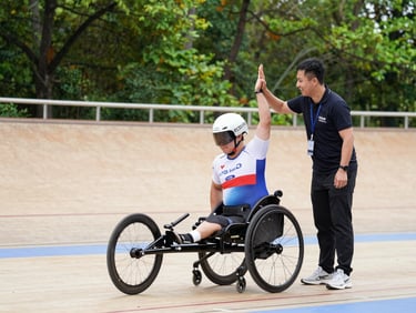 An adaptive athlete in a specialized racing wheelchair participating in an outdoor track event, high-fiving a smiling volunteer coach.