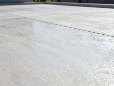 Close-up of a decorative concrete patio with a subtle texture, bright cool daylight, low angle, high depth of field, sharp industrial photography.