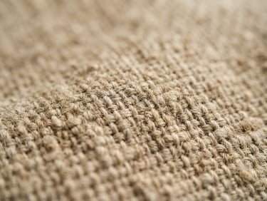 Macro shot of textured natural linen fabric, soft daylight, warm neutral tones, shallow depth of field.