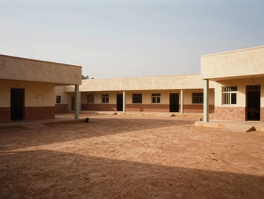 Wide shot of the CFP Ourossogui campus courtyard, warm afternoon Sahelian sun casting soft shadows on the modern workshop buildings