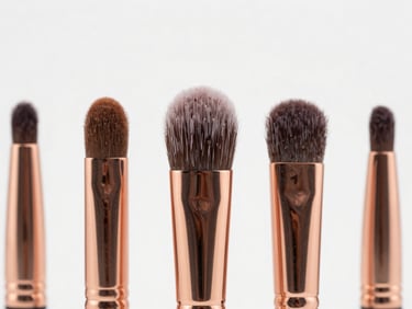 Macro close-up of premium cosmetic brush heads, rose-gold metal ferrules, white minimalist background.