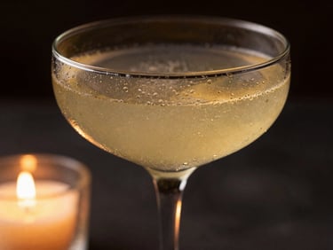 Macro shot of a vibrant botanical cocktail in a coupe glass, condensation on the glass, low-key side lighting, elegant atmosphere.