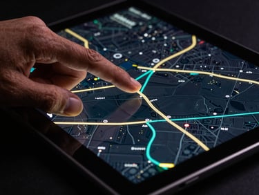 Close-up of a hand interacting with a rugged Android tablet screen showing a dark-mode map, sharp LED reflections