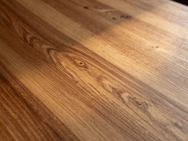 Dramatic close-up of raw polished timber grain with golden side-lighting, showcasing the structural texture and premium finish of grade-A teak.