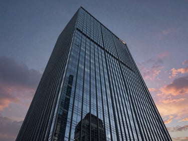 Low-angle elevation of a commercial office tower, dramatic twilight sky, precise glass reflections