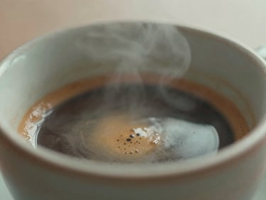 Close-up of a dark, rich espresso shot being pulled into a ceramic cup, steam rising gently, soft morning light, earthy tones, shallow depth of field, 35mm