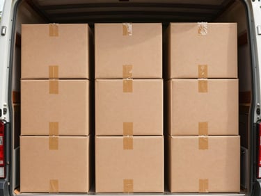 Neatly stacked double-walled fiberboard boxes inside a clean, modern moving truck, labeled clearly, bright daylight.