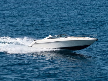 Action shot of the Noel speedboat cutting through calm, deep blue water, spray visible, low-angle perspective.