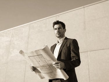 Monochromatic portrait of a confident man with an architectural blueprint in background, golden hour light, editorial style