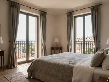 Spacious master bedroom in Valencia apartment, large balcony doors showing traditional iron railings, neutral stone gray textiles, warm natural daylight, clean composition