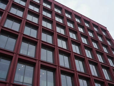Architectural details of a newly completed modern commercial building facade, sharp architectural lighting, low-angle hero shot, deep crimson and graphite tones