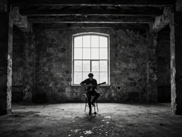 A monochrome wide shot of a live acoustic session in an abandoned stone warehouse, soft window light highlighting dust motes, Guillem playing guitar in the center, minimalist composition.