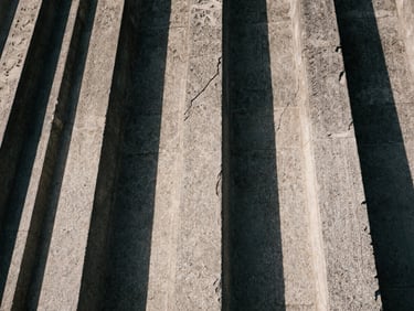 Extreme close-up of weathered stone carvings on a historic building facade, deep shadows highlighting the cracks and erosion