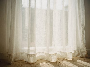 Soft diffused morning light filtering through a sheer linen curtain, warm sand tones, shallow depth of field, 35mm film aesthetic