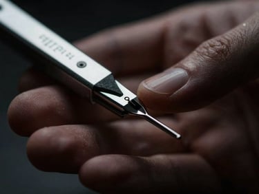 Moody dark-mode photography, macro close-up of a professional hand holding a silver steel dermograph, dramatic side-lighting, high contrast, sharp focus on the needle tip