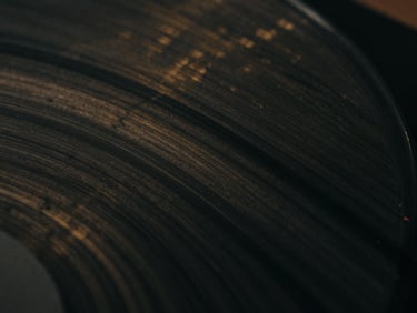 extreme close-up of marbled vinyl surface, deep charcoal and subtle gold patterns, low-key lighting, atmospheric cinematic photography, deep shadows, moody desaturated tones, 35mm film