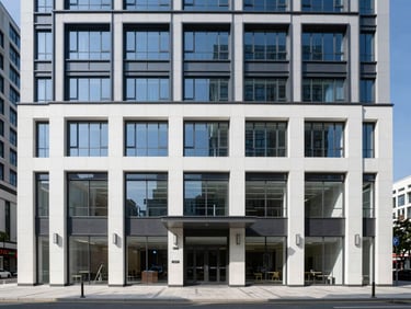 Modern mixed-use building exterior combining ground-floor storefronts with upper-level corporate suites, clean architectural lines